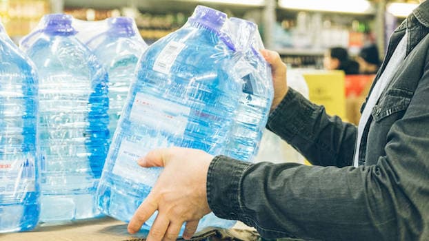 VISION AQUA Wasserfilter - keine Getränke kaufen und lagern Mann nimmt verpackte Wasserflaschen in die Hand