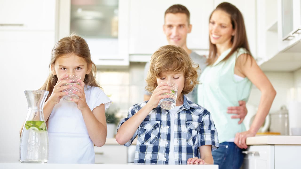 Verdanium MAX Wasserfilter - Sicheres, sauberes und leckeres Trinkwasser für die ganze Familie Kinder trinken sauberes Wasser aus einem Verdanium MAX Wasserfilter in der Küche