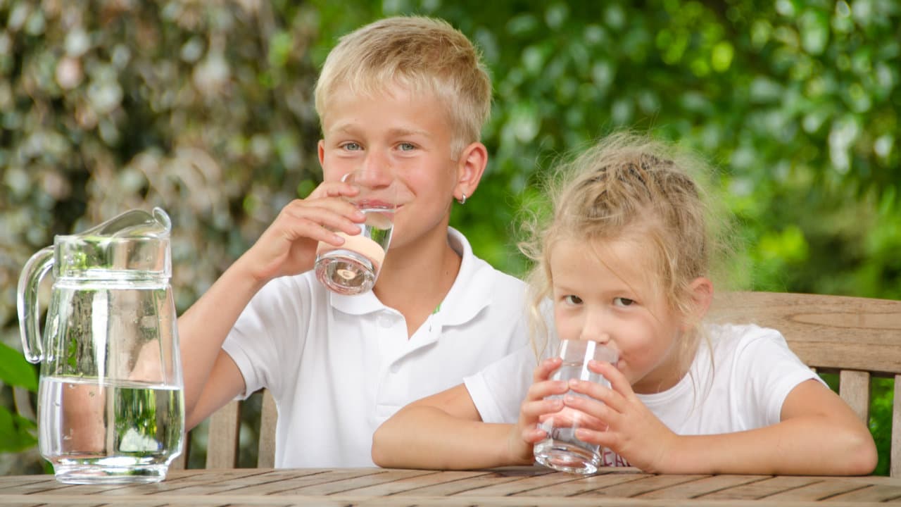 Kinder trinken sauberes Wasser von VISION AQUA im Garten