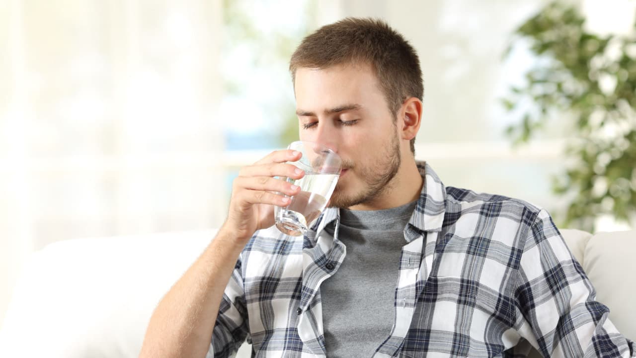 VA-Mini -Der perfekte Wasserfilter für Singles und kleine Haushalte Junger Mann trinkt sauberes Wasser aus einem VA-Mini Wasserfilter von VISION AQUA